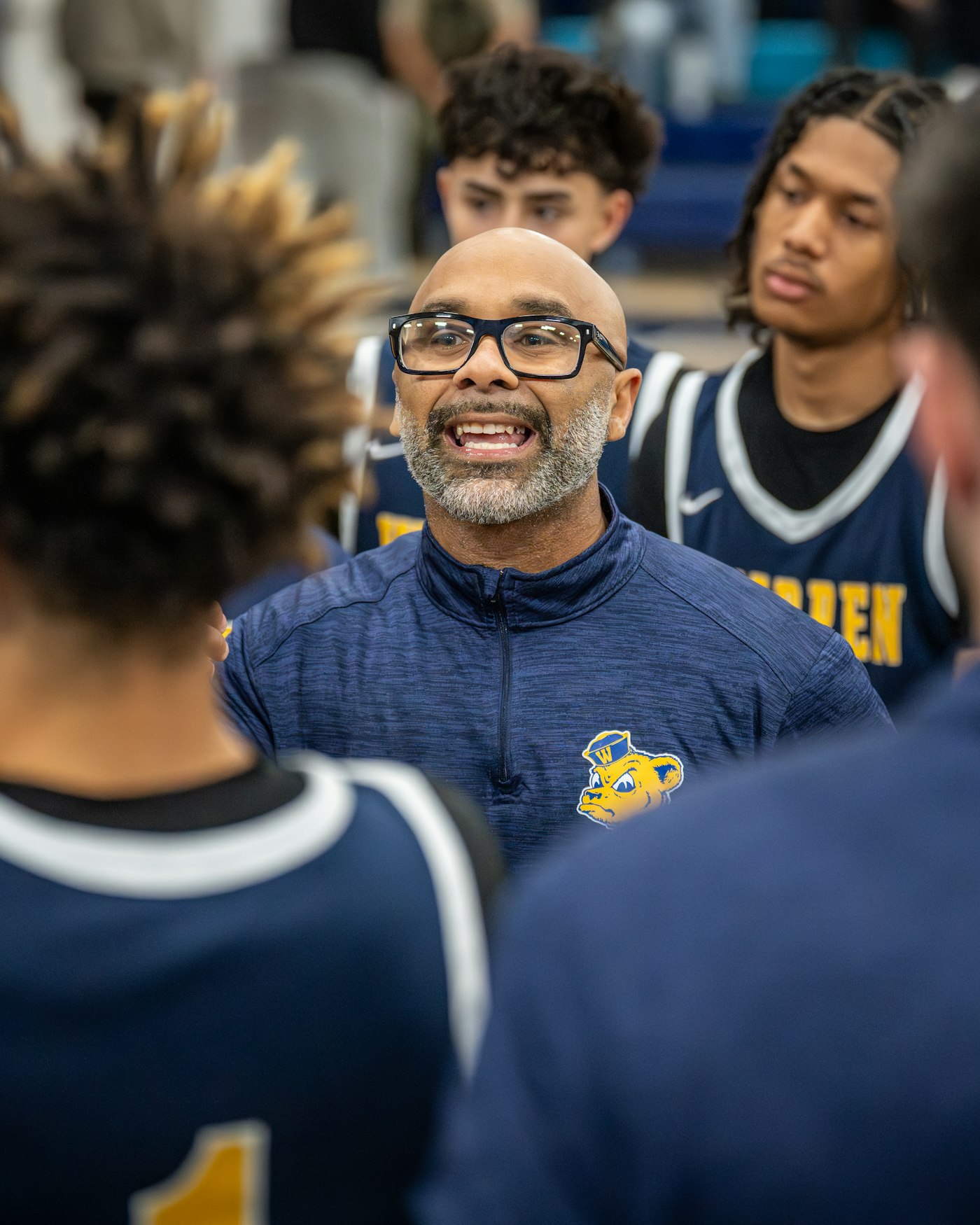 A coach giving instructions to players during a huddle